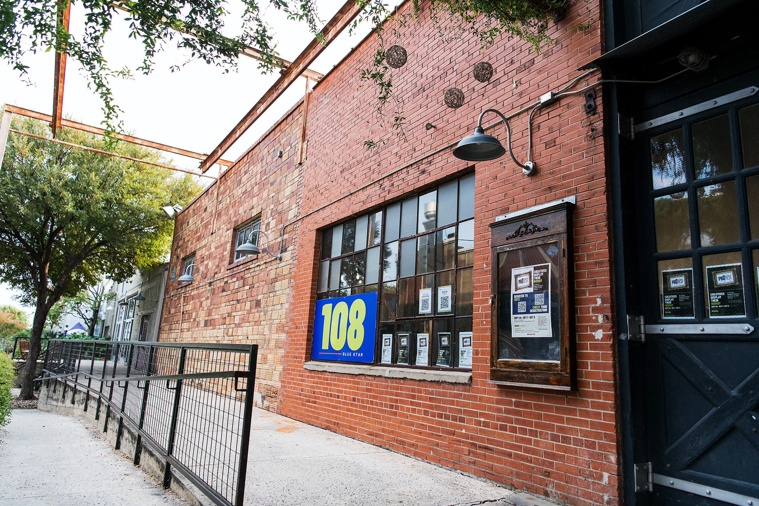 The brick facade and tall black doors at the entrance to 108 Blue Star in the Blue Star Arts Complex