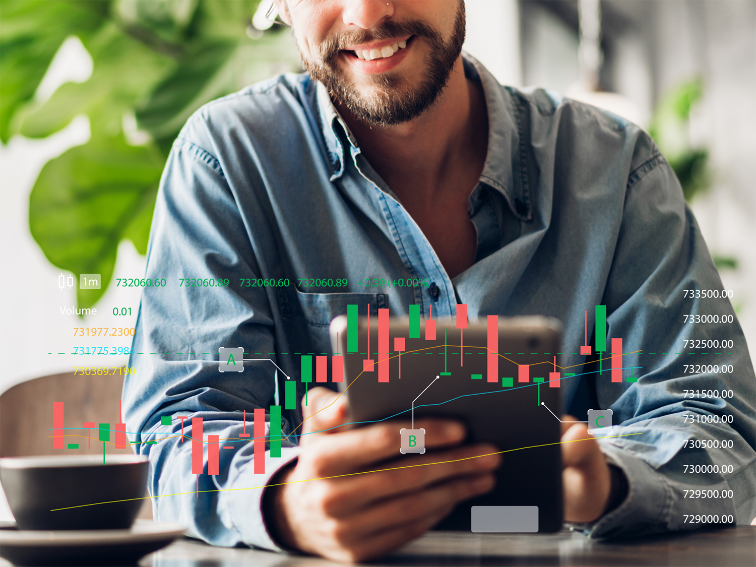 Smiling man wearing a denim shirt holding a tablet with a superimposed financial candlestick chart showing stock price movements and volume data, with green and red bars, lines, and numerical values.