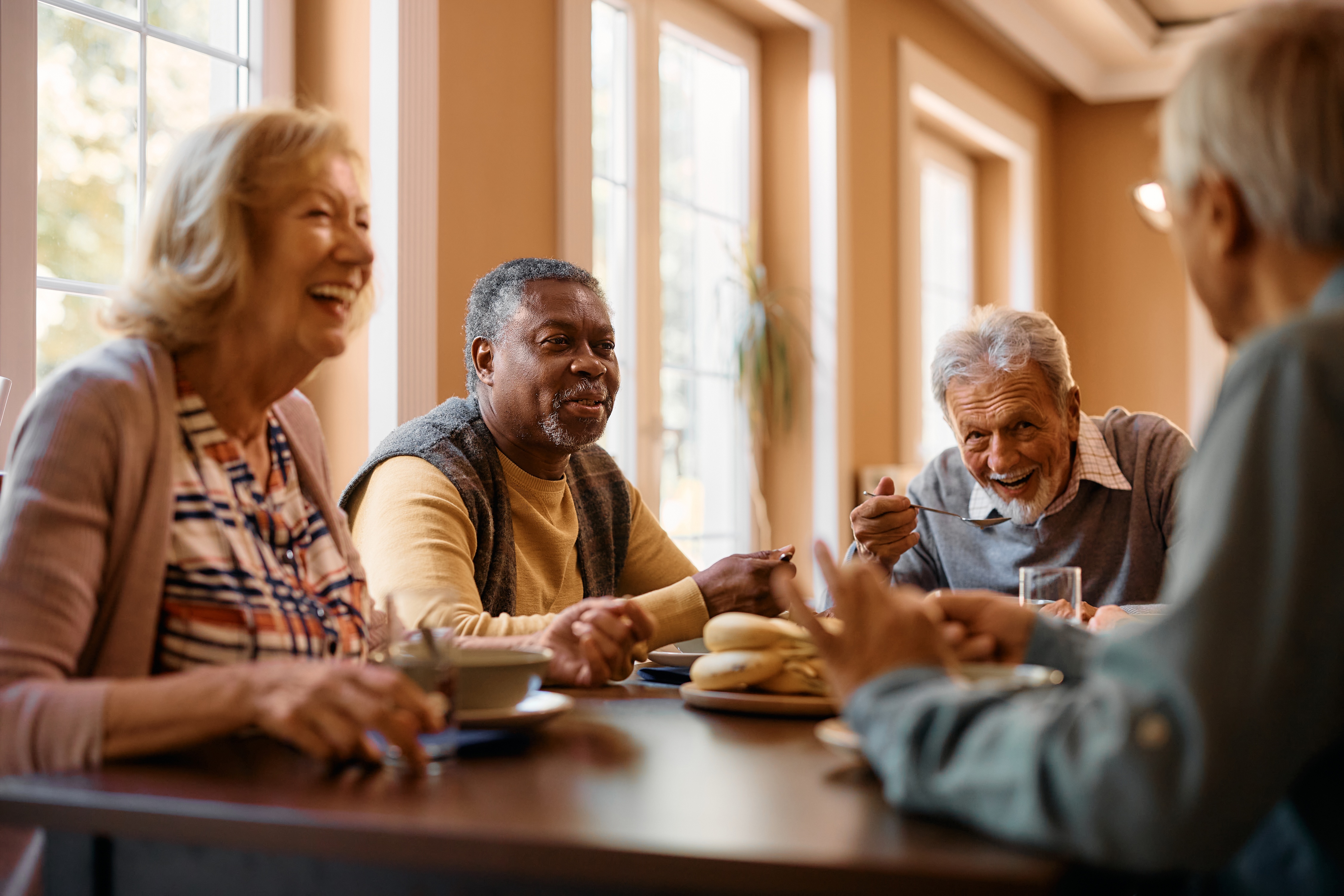 Senior men and women sitting at a table laughing and eating stock image