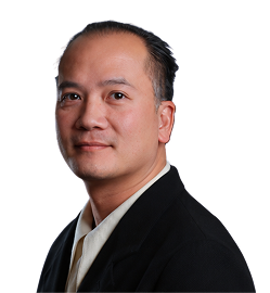 Portrait of a middle-aged man with short black hair combed back, wearing a black jacket and beige shirt, looking slightly to the side against a white background.