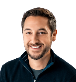 Smiling man with short dark hair and beard wearing a black zip-up jacket over a dark shirt, with a white background.