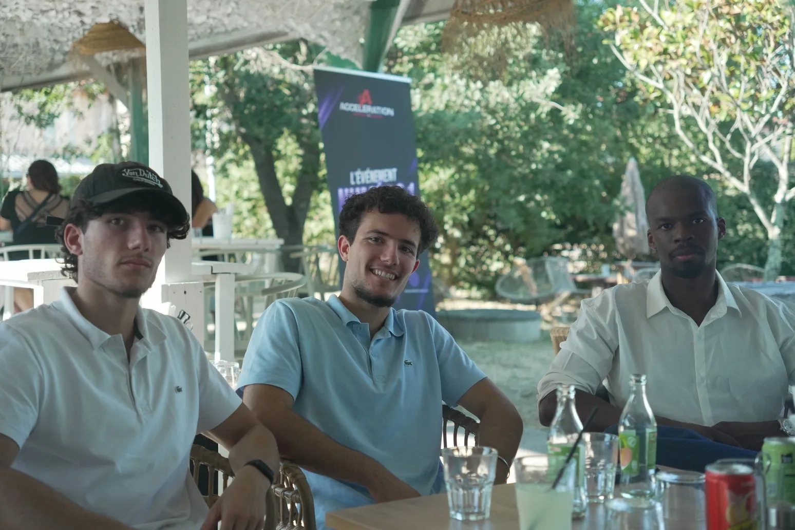 Trois participants souriants attablés en terrasse lors d'un afterwork Accélération.