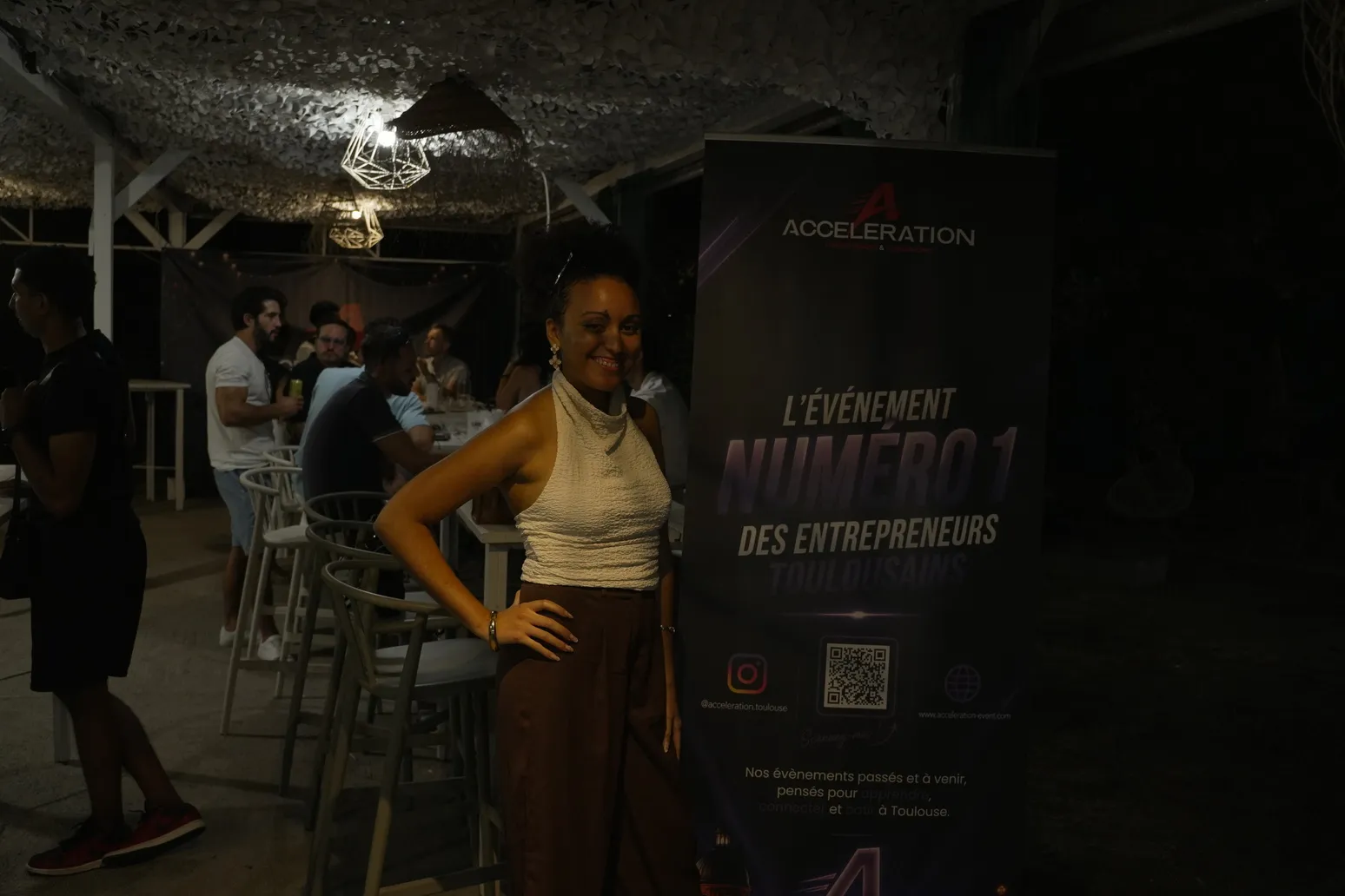 Participante posant devant le kakémono Accélération lors d'une soirée en extérieur.