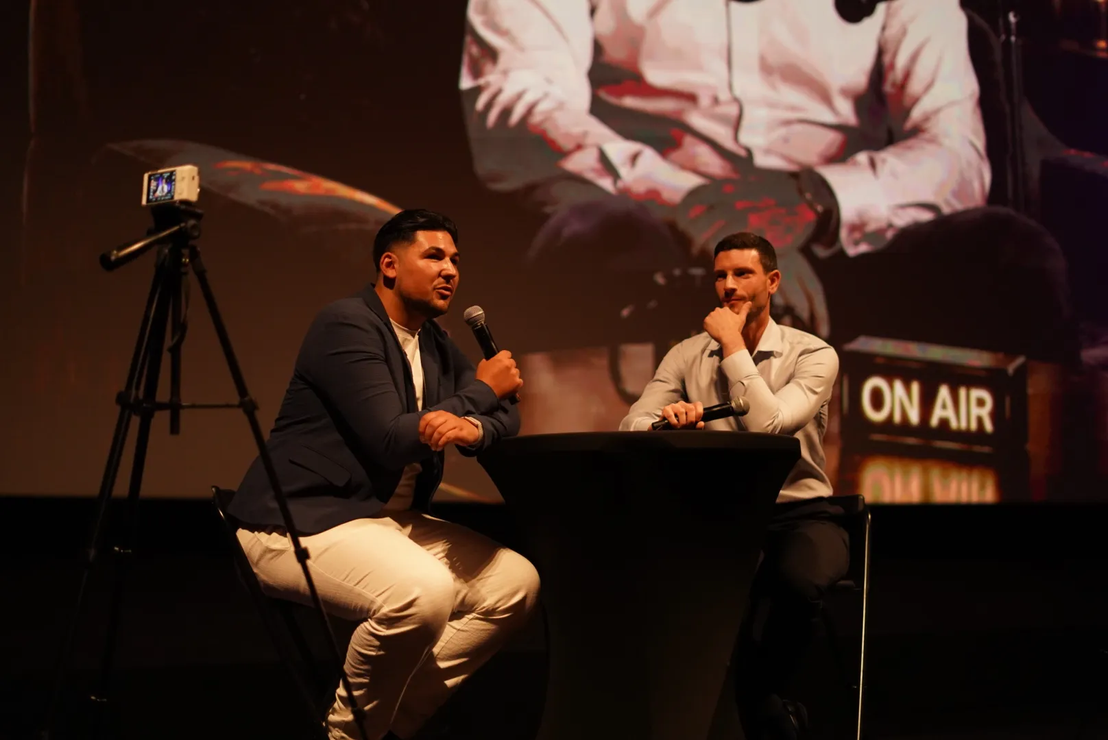 Deux intervenants échangent sur scène façon plateau télé, panneau ON AIR en arrière-plan, lors d'Accélération.