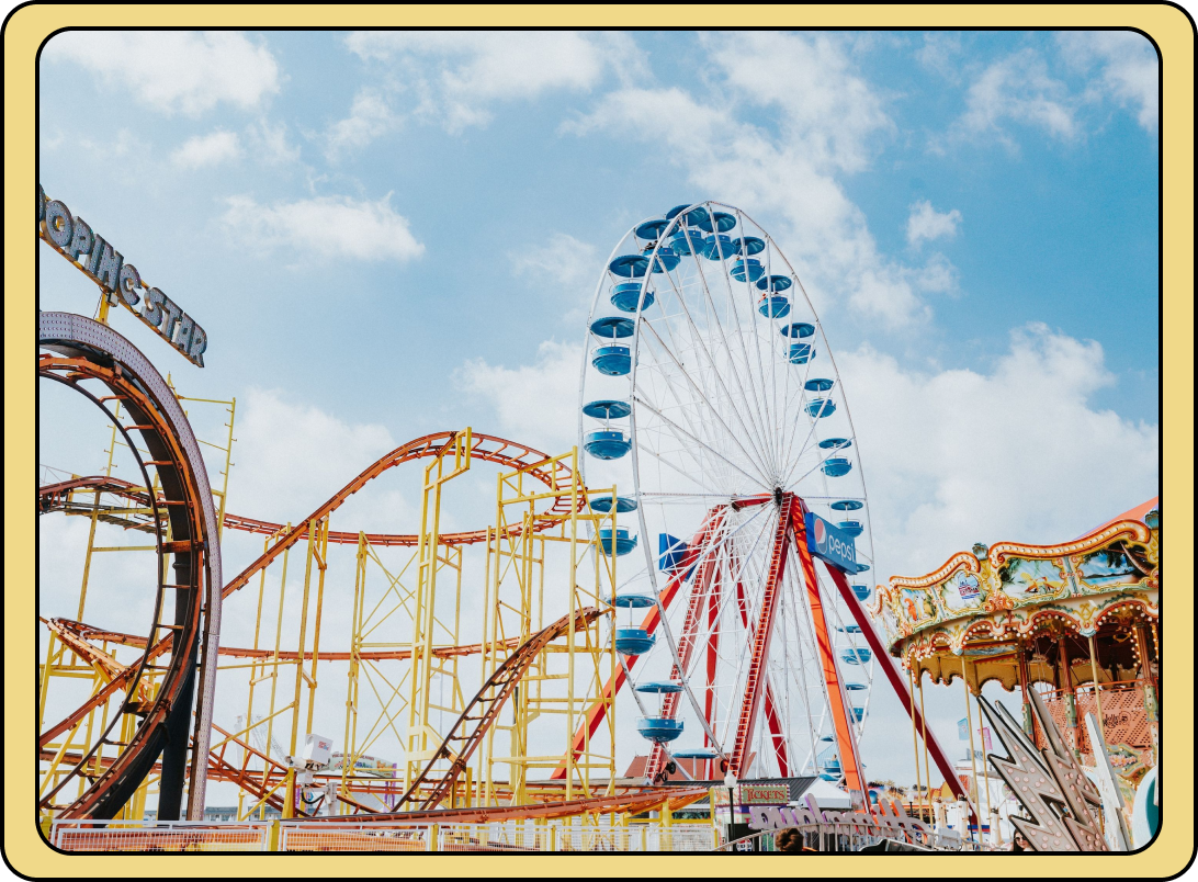 Ferris wheel, roller coaster, and carousel under a blue sky