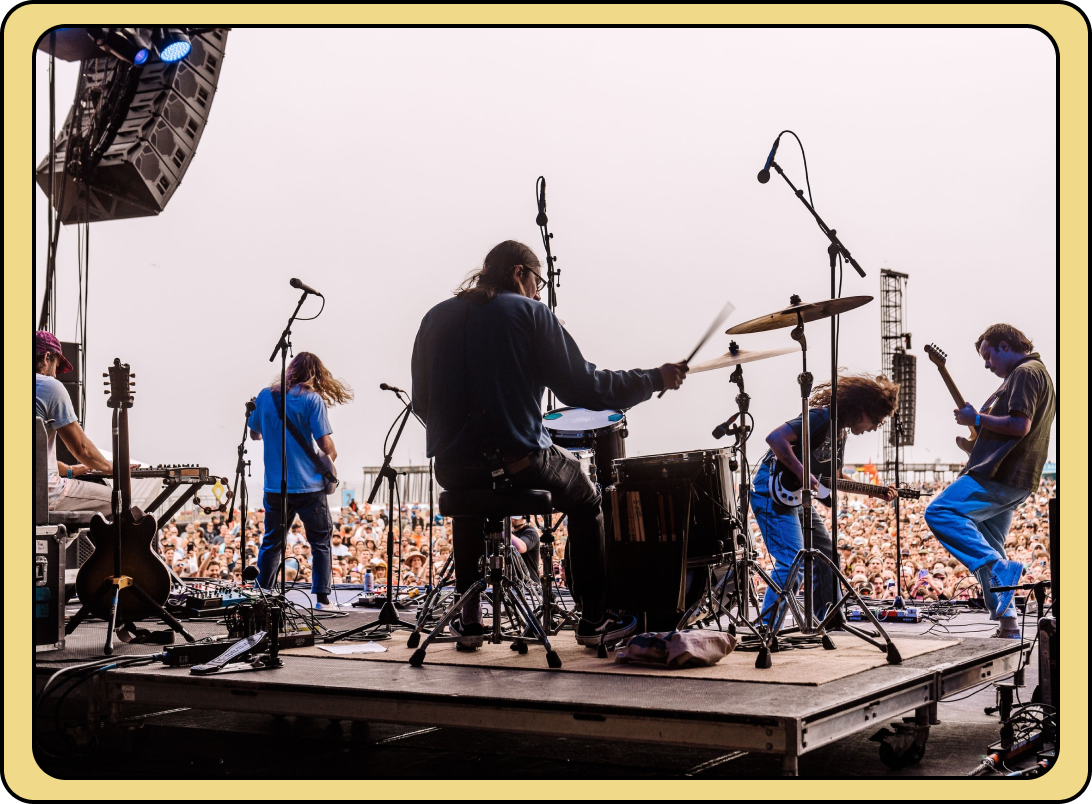 Rock band performing on an outdoor stage in front of a large crowd
