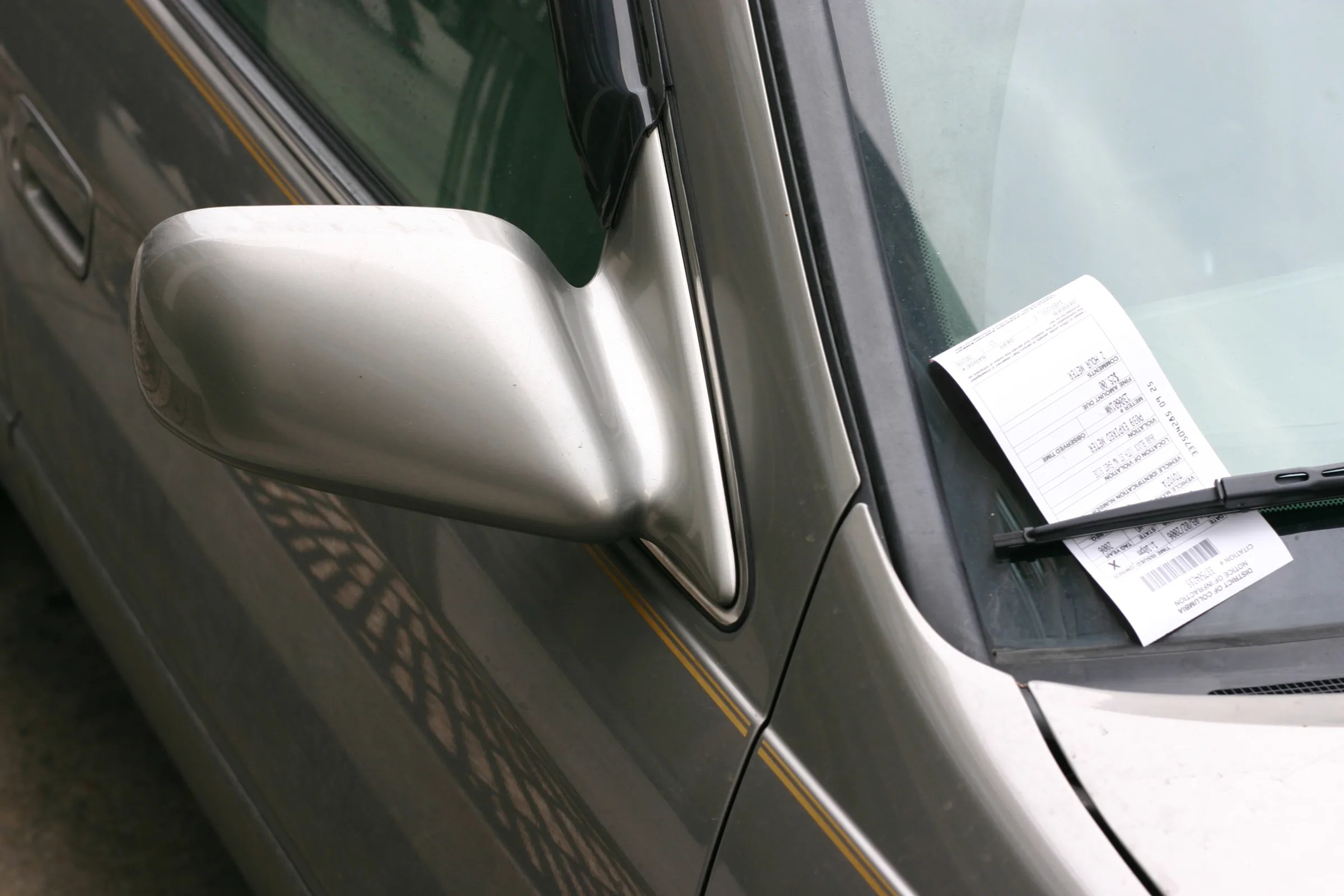 Traffic ticket tucked under a car windshield wiper