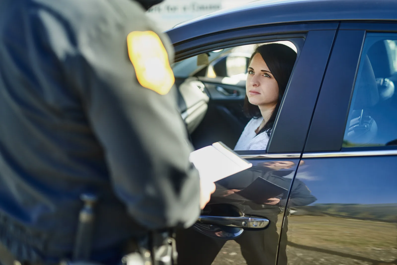 Driver handing a license to a police officer during a traffic stop