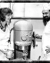 Two bakers standing at the big floor mixer