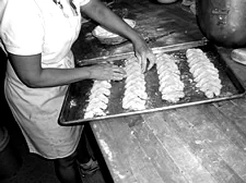 A baker laying rows of filled cheese kuchen onto a sheet pan