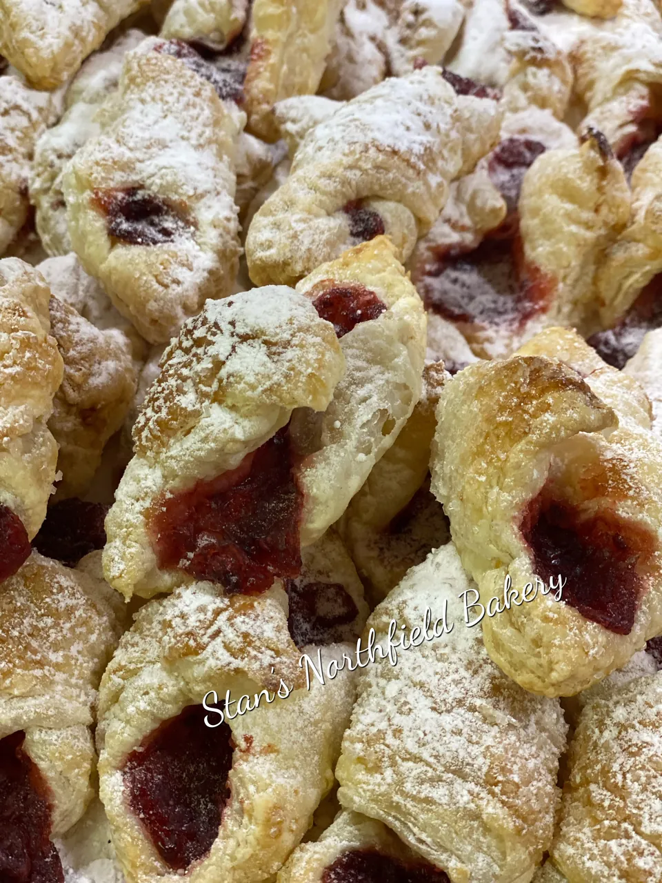 Puff pastry kolacky filled with fruit and dusted with powdered sugar
