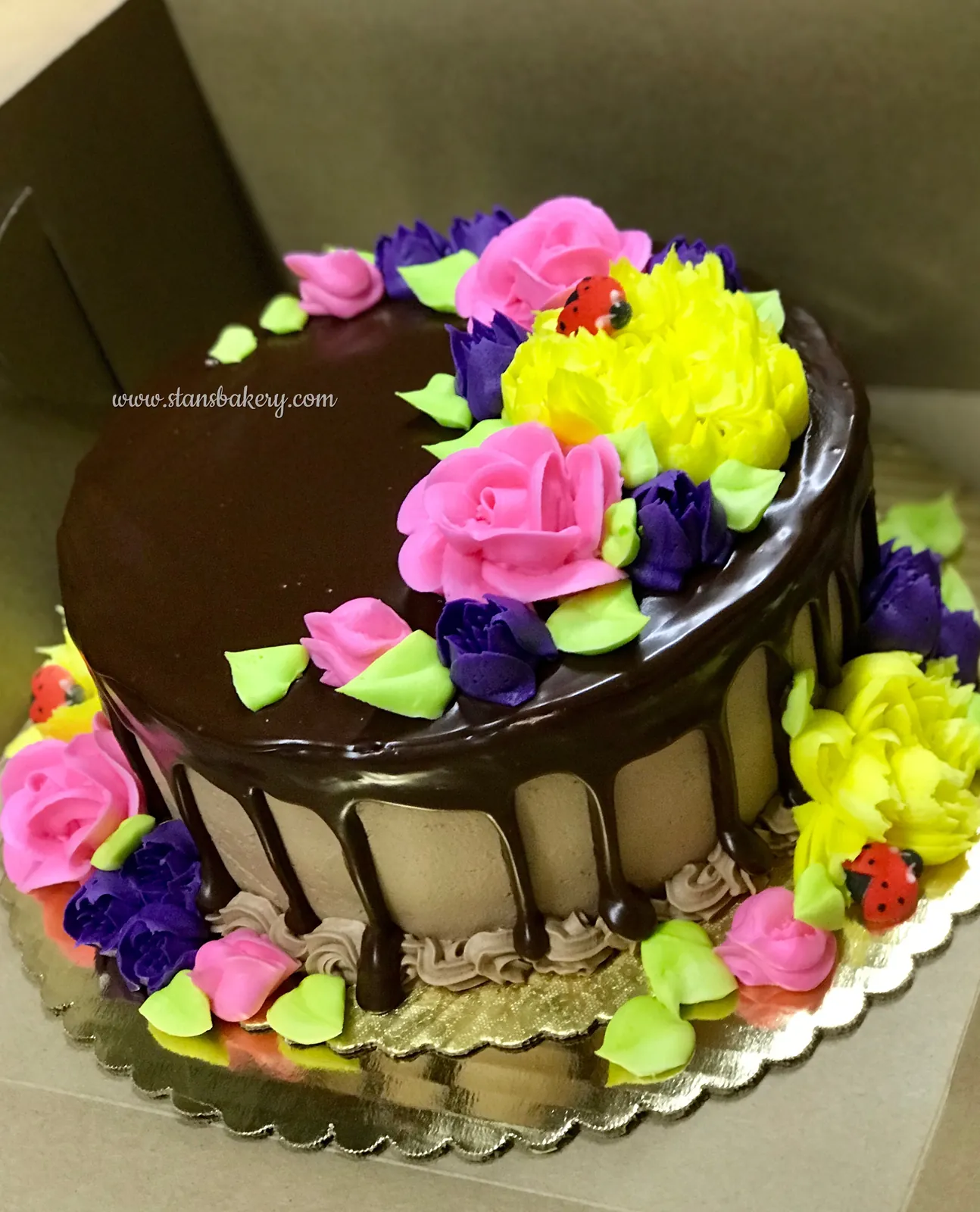 A chocolate drip cake crowned with bright flowers