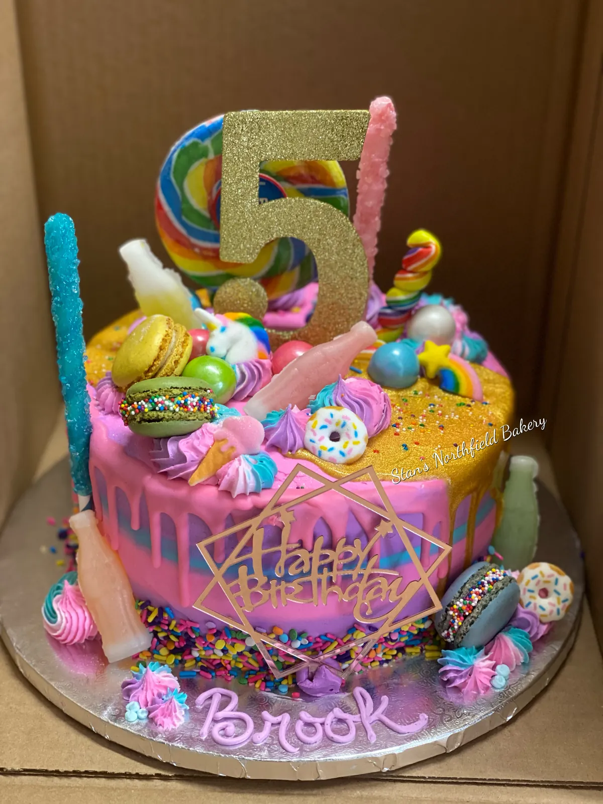 A drip cake loaded with candy and a number five