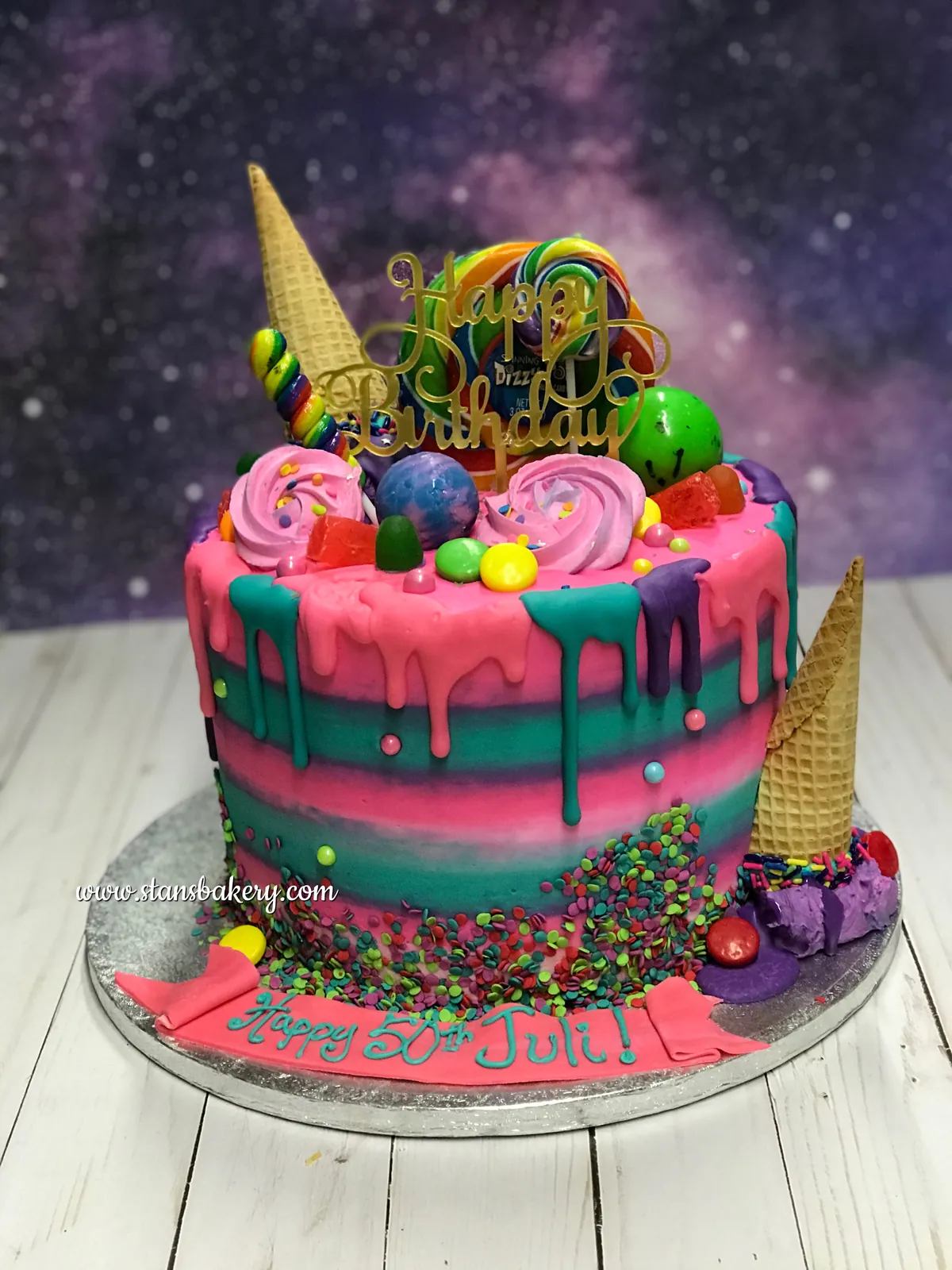 A galaxy-colored drip cake with sweets on top