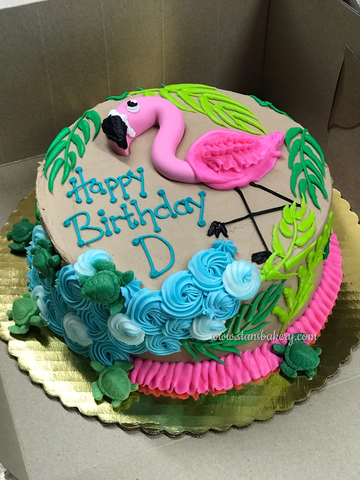 A birthday cake with a fondant flamingo and palm leaves