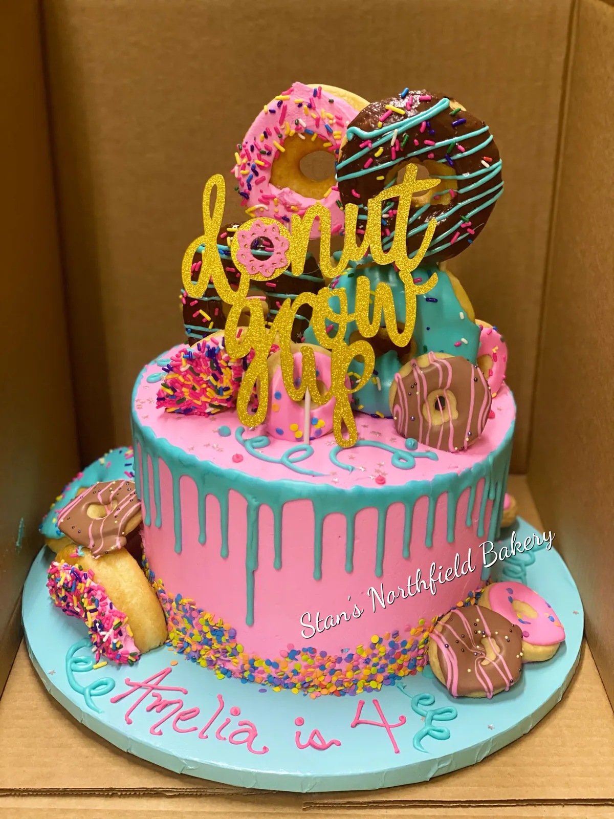 A pink drip cake topped with donuts