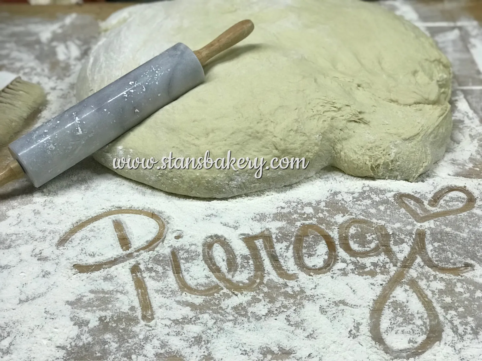 Pierogi dough with the word pierogi written in flour and a rolling pin
