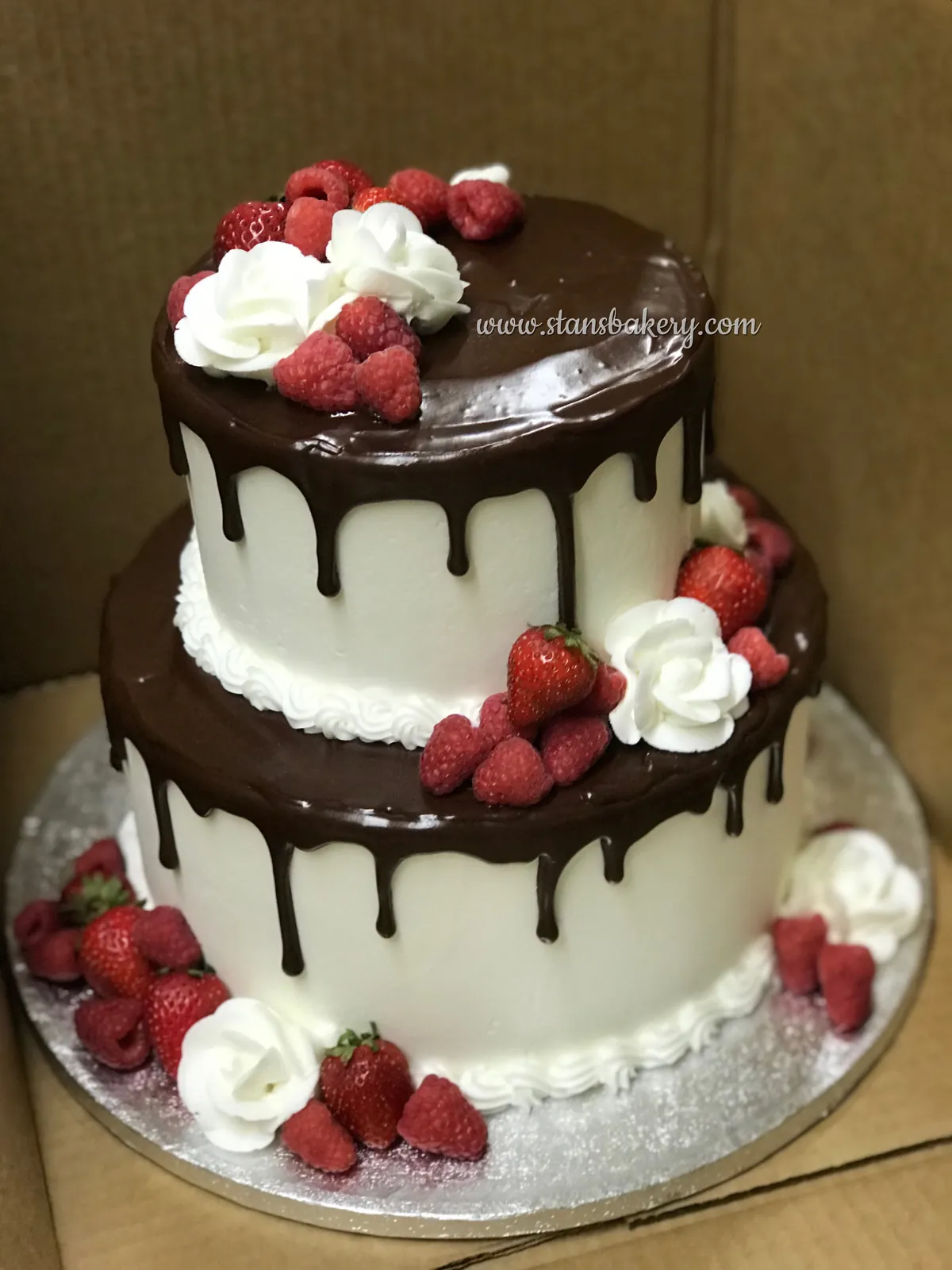 A chocolate drip cake with raspberries and strawberries