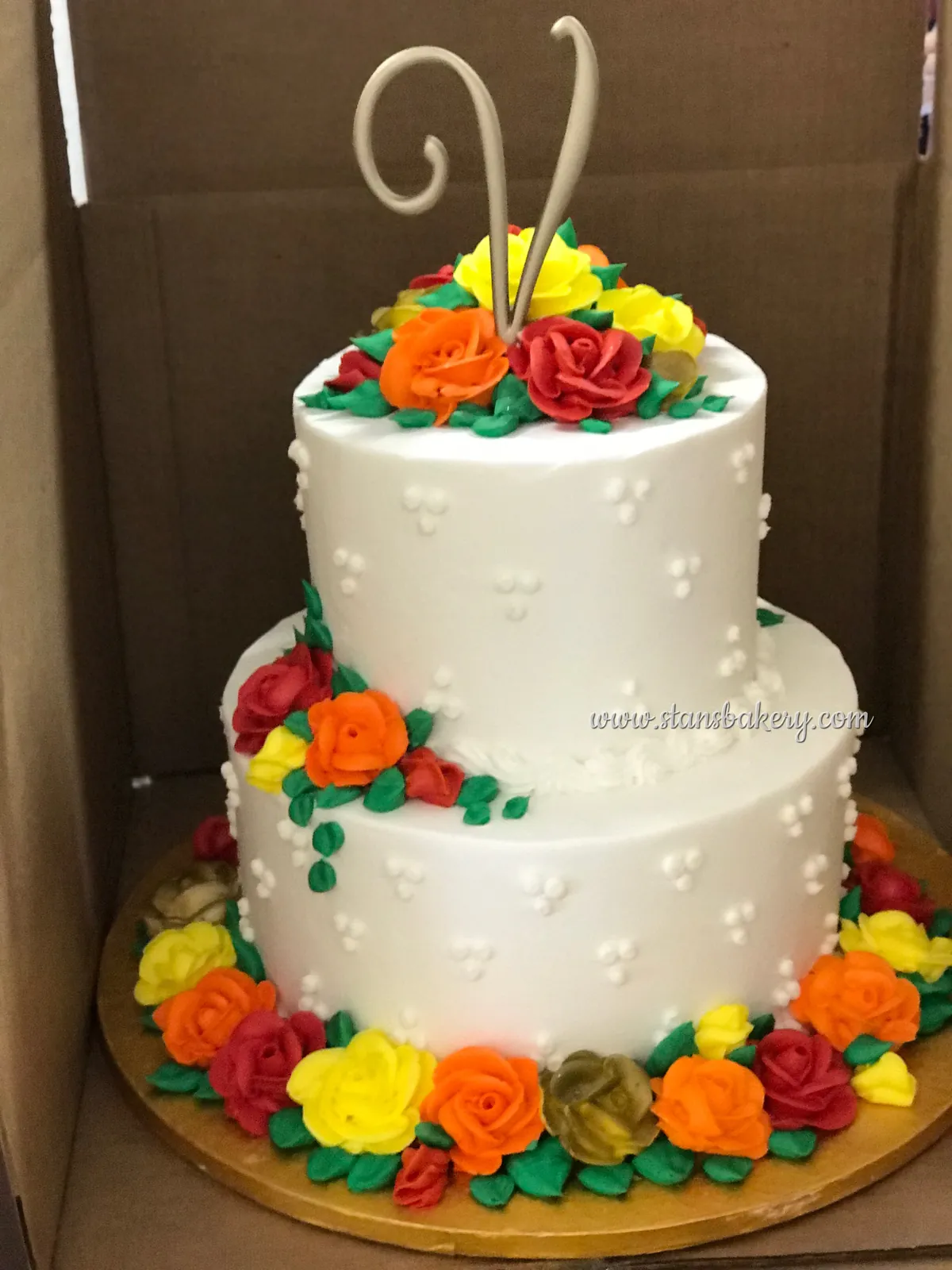 A white two-tier cake with orange and red sugar flowers