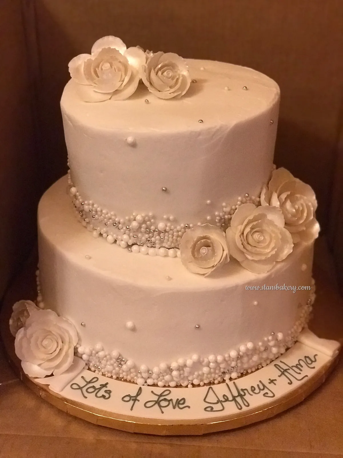 A blush two-tier cake with roses and pearls