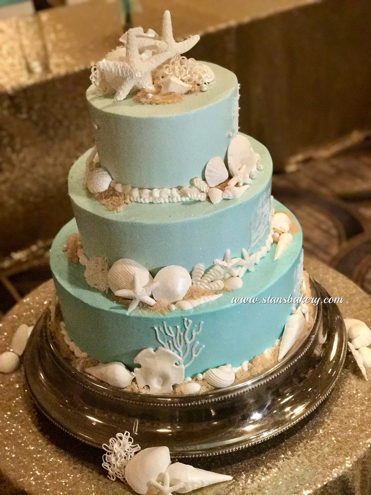 A pale blue tiered cake with sugar seashells