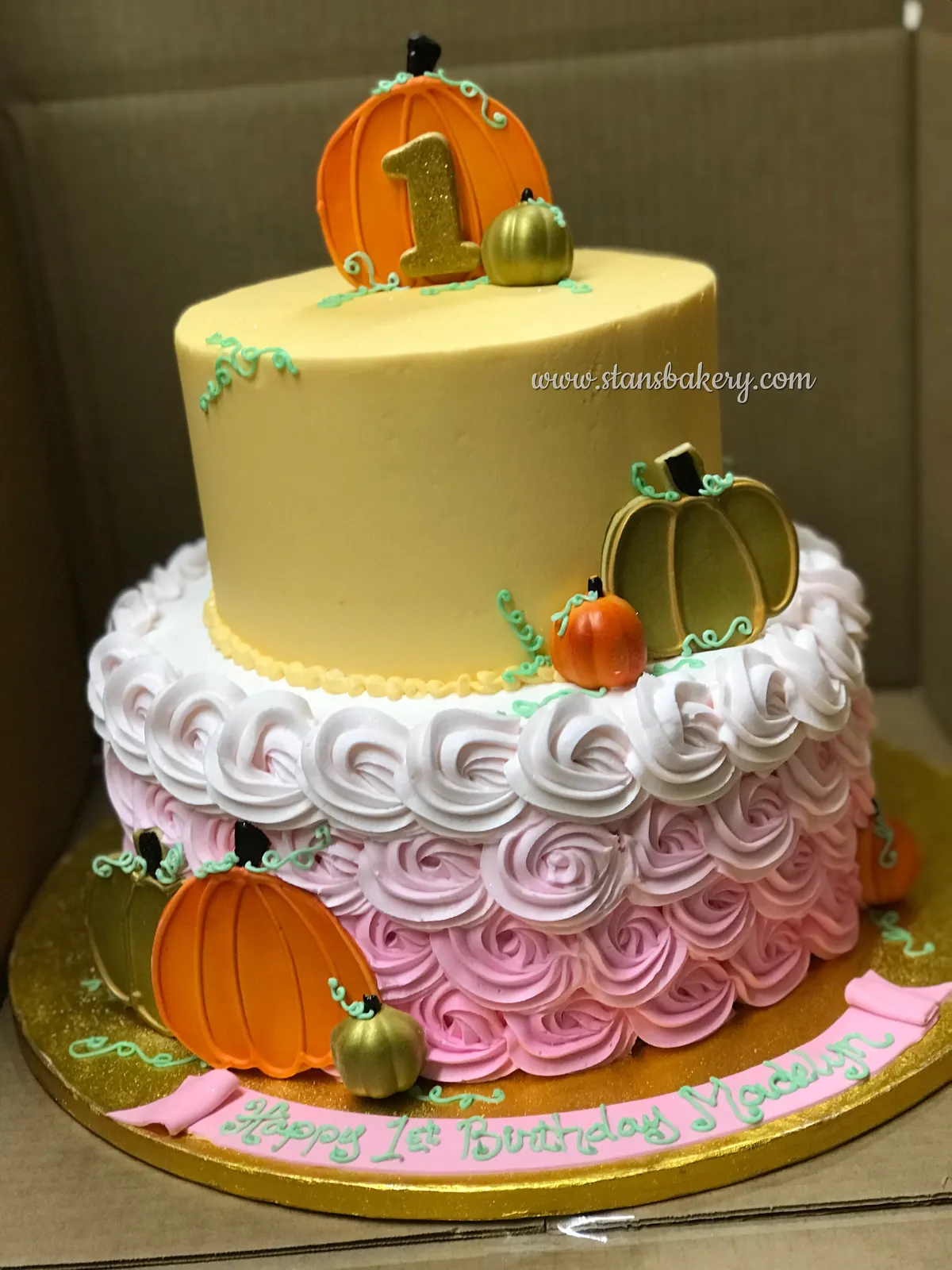 A first-birthday cake with pumpkins and rosettes