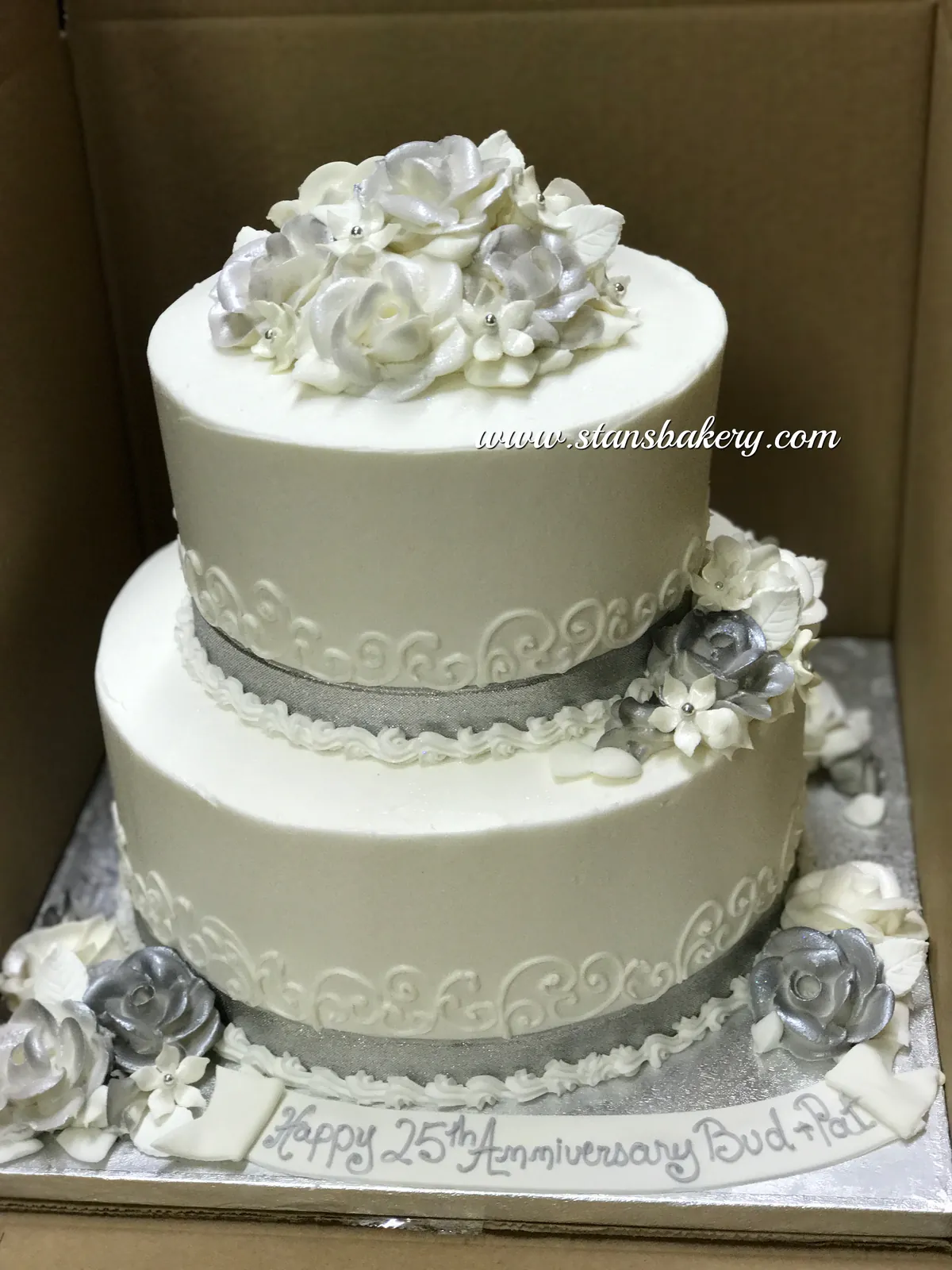 A white two-tier cake topped with white roses
