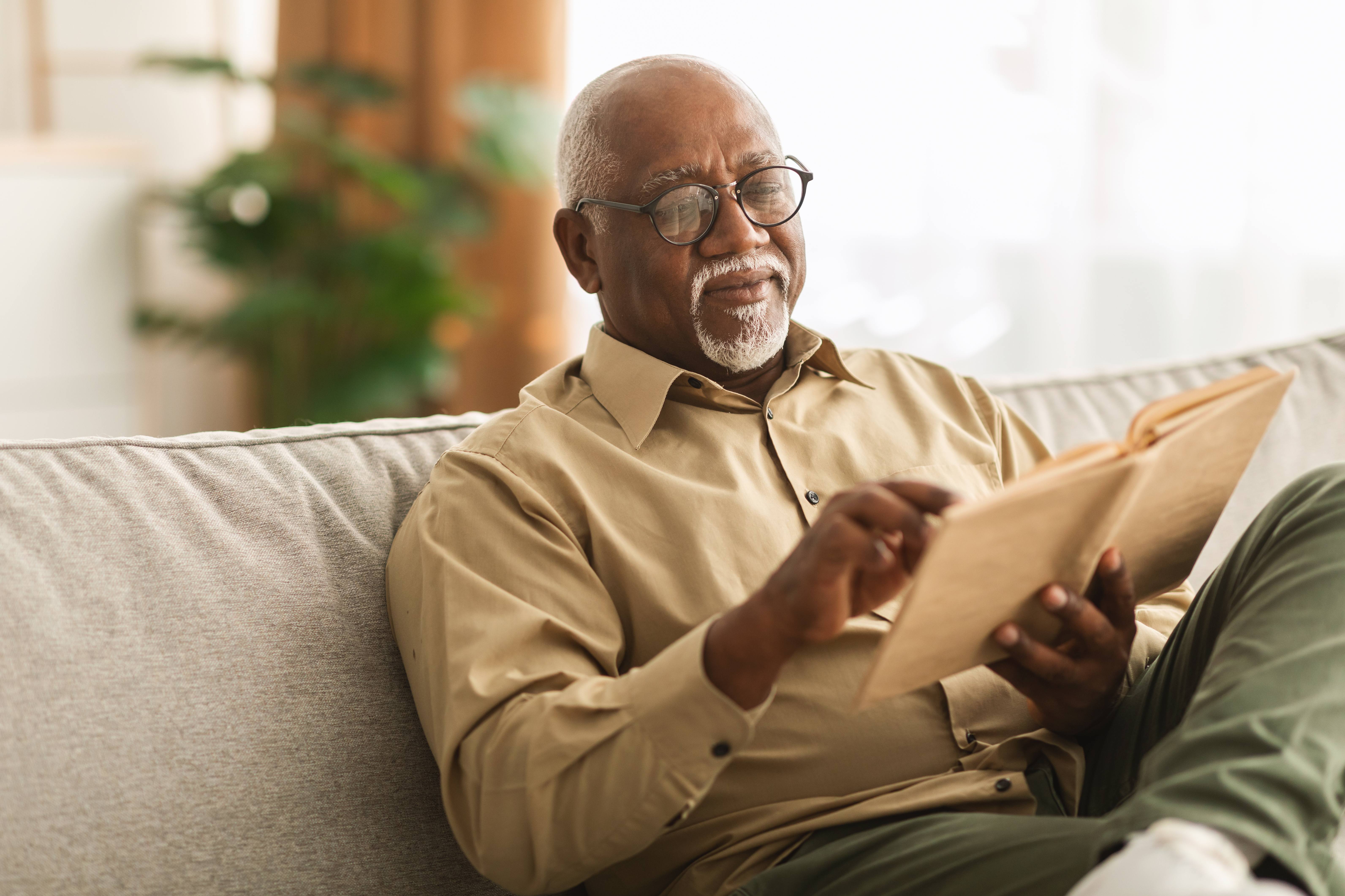 Man reading a book while sitting on the couch stock image