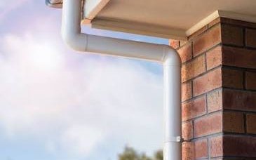 Downpipe elbow joint against a brick wall corner