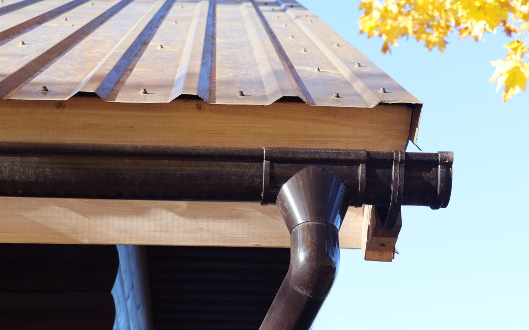 Close-up of a seamless gutter and downpipe elbow on a metal roof