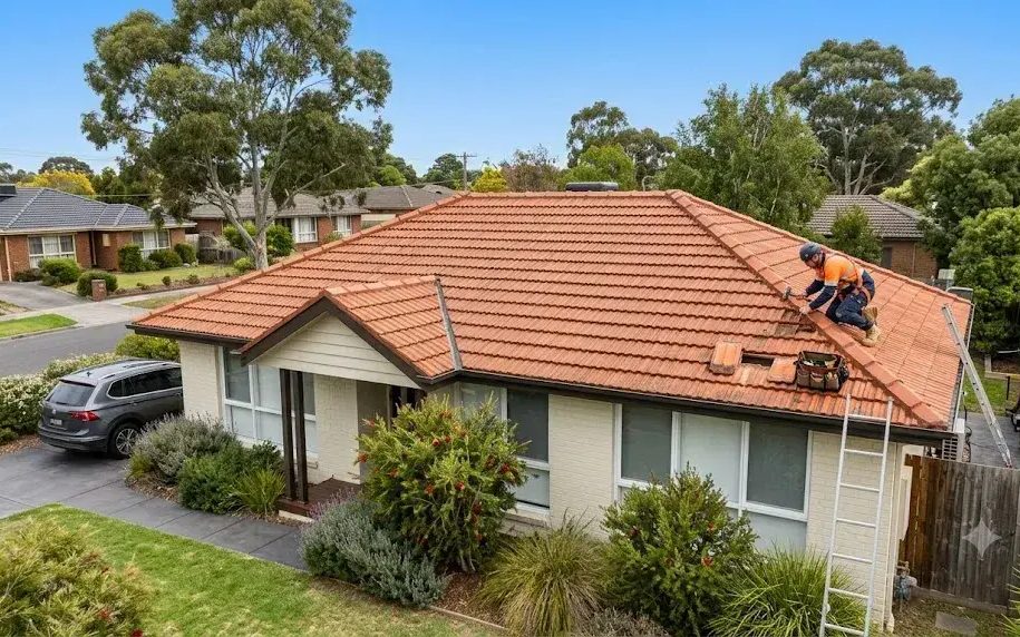 Roofing technician repairing tiled roof on a residential home