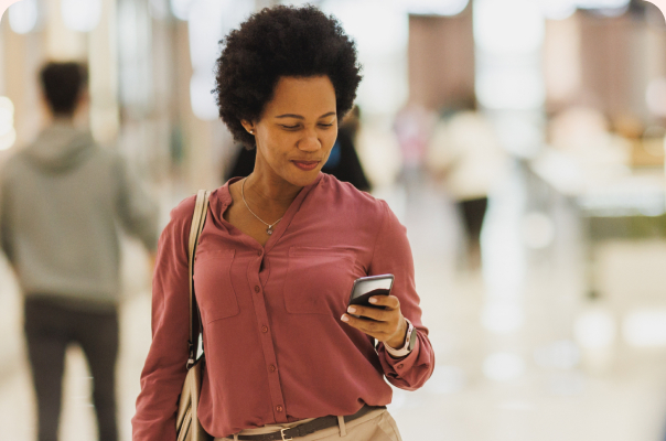 Woman smiling at her phone while walking through a shopping center
