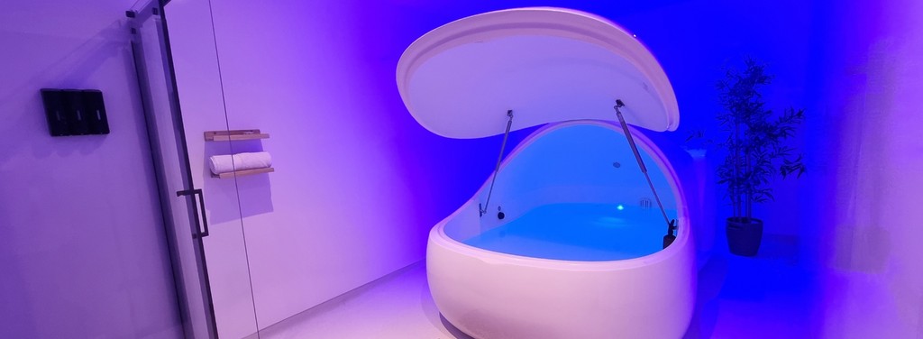 An open Float Pod glowing blue in a private room at Floatworks Angel