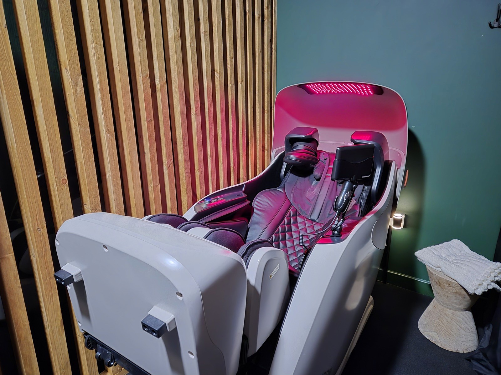 Red Light Therapy Massage Pod with its red light panel glowing, in a bright minimal room