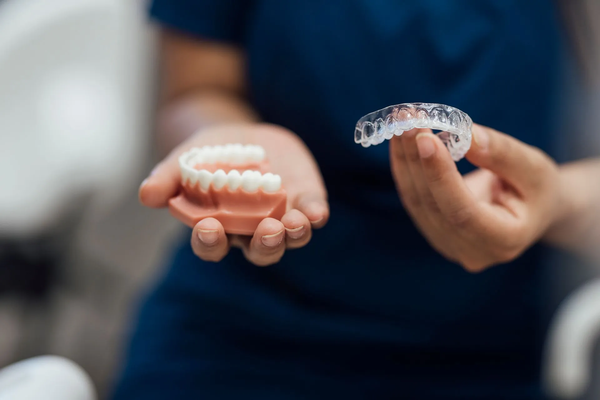 Orthodontist holding a clear aligner and a dental model