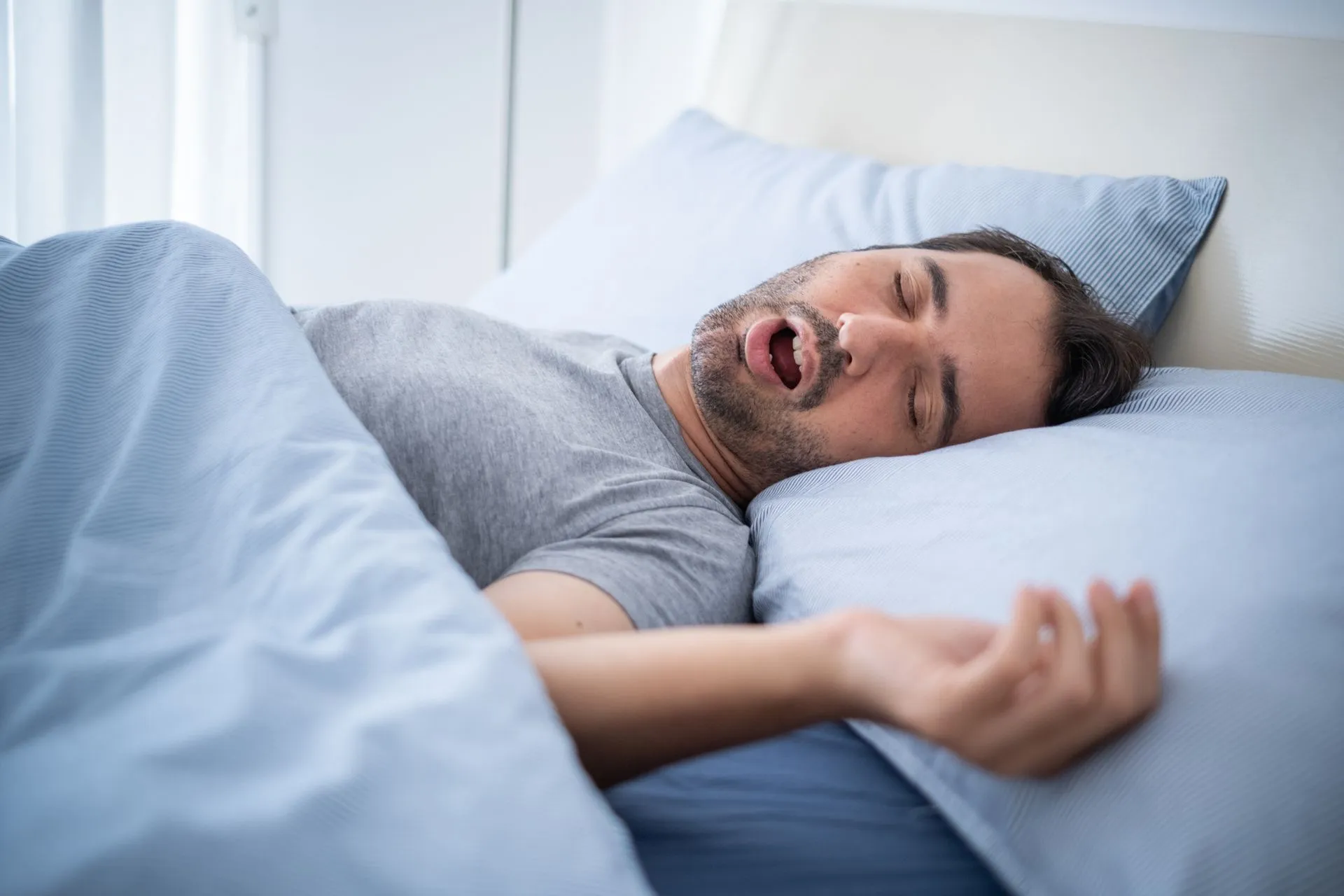 Man asleep in bed breathing through his open mouth