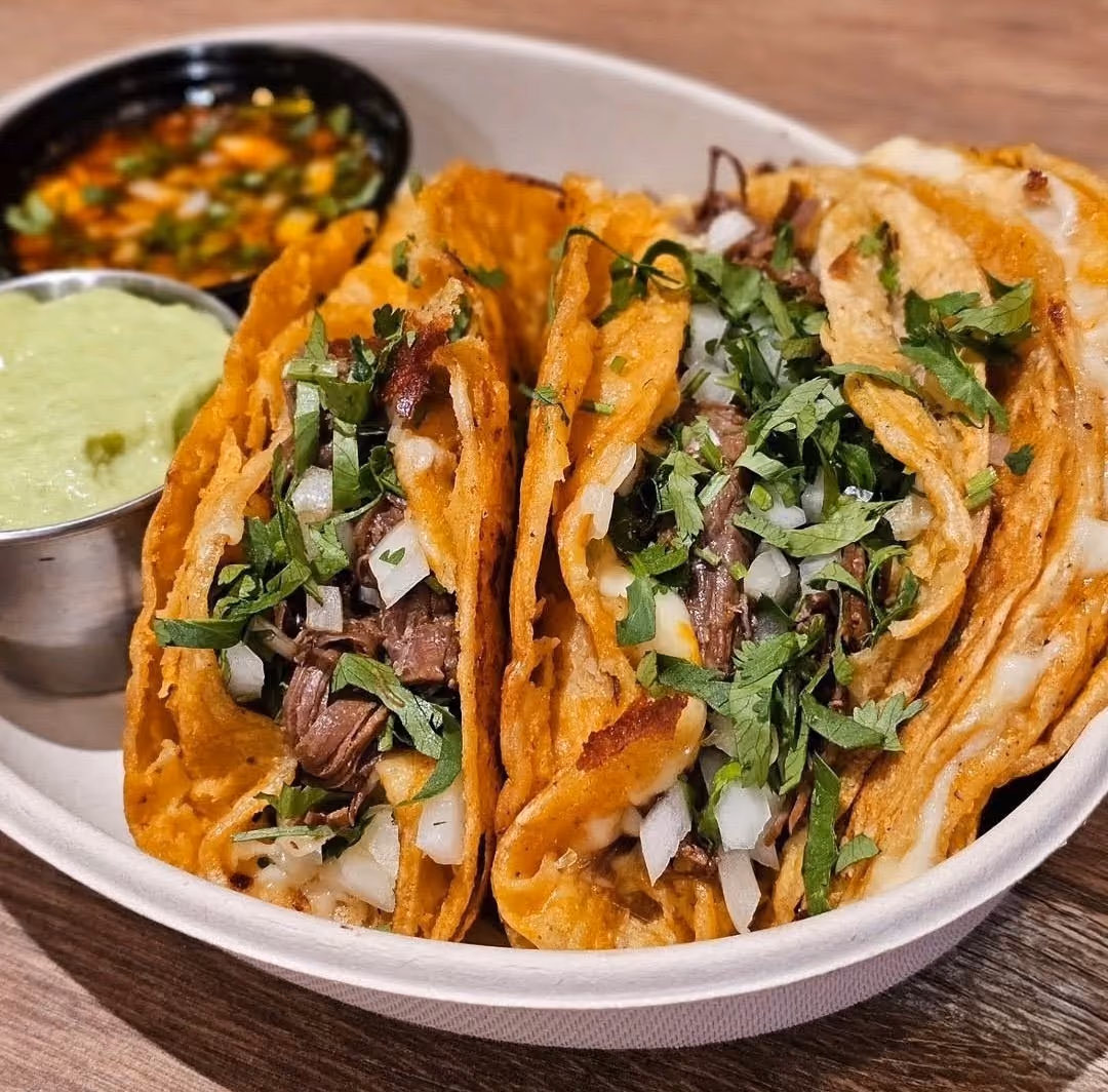 Cheese-crisped birria tacos with cilantro and onion at Don Chuy's Taqueria
