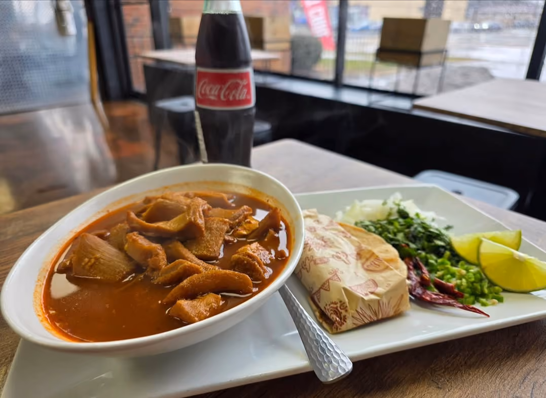 Bowl of menudo with tortillas, lime, and a Coca-Cola at Don Chuy's Taqueria