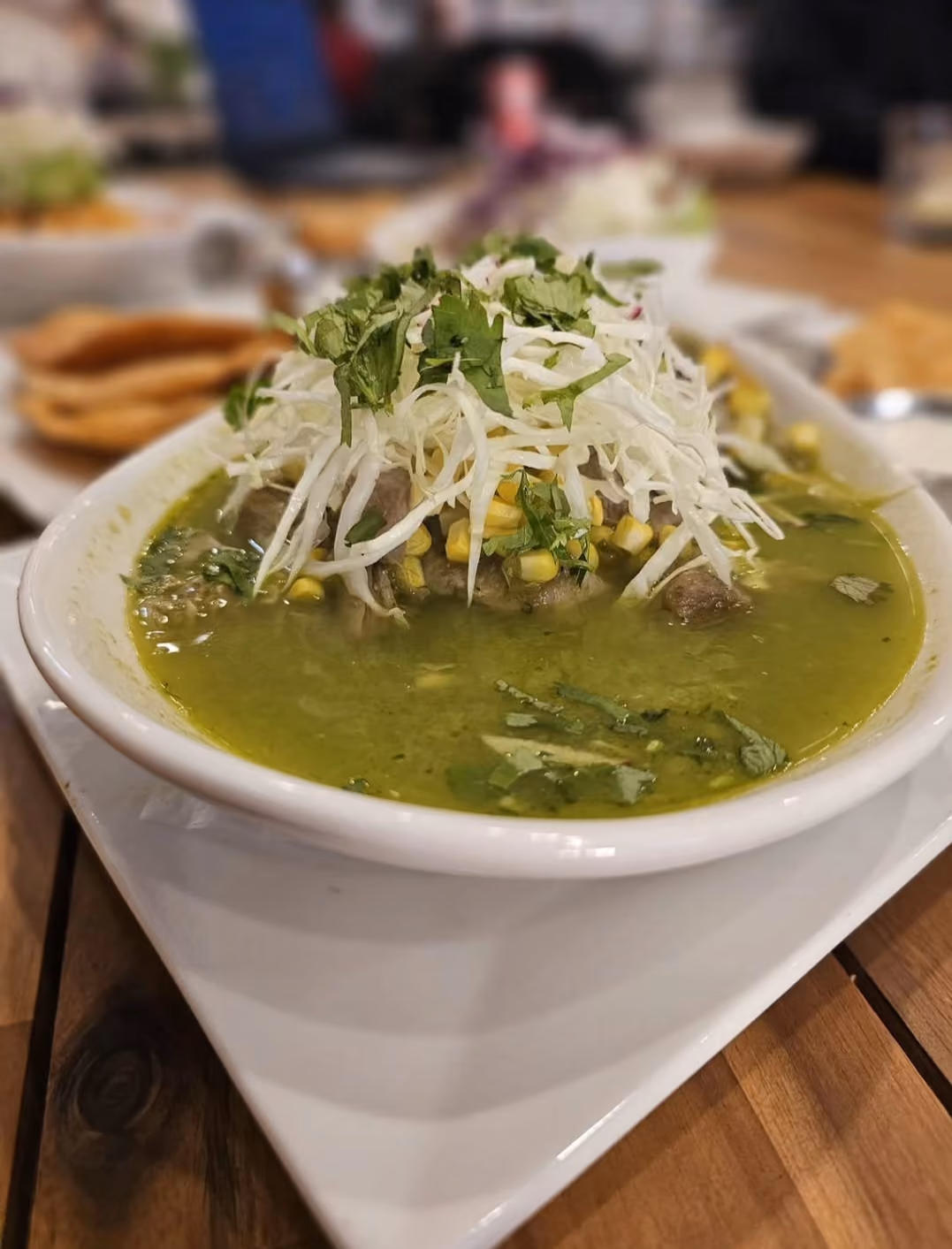 Bowl of green menudo soup topped with cabbage and cilantro
