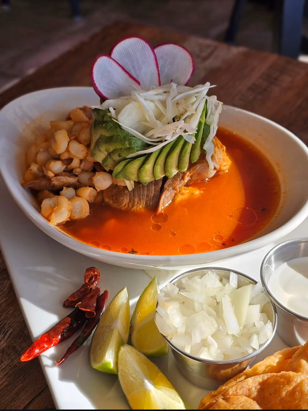 Bowl of red pozole with hominy, avocado, and lime at Don Chuy's Taqueria
