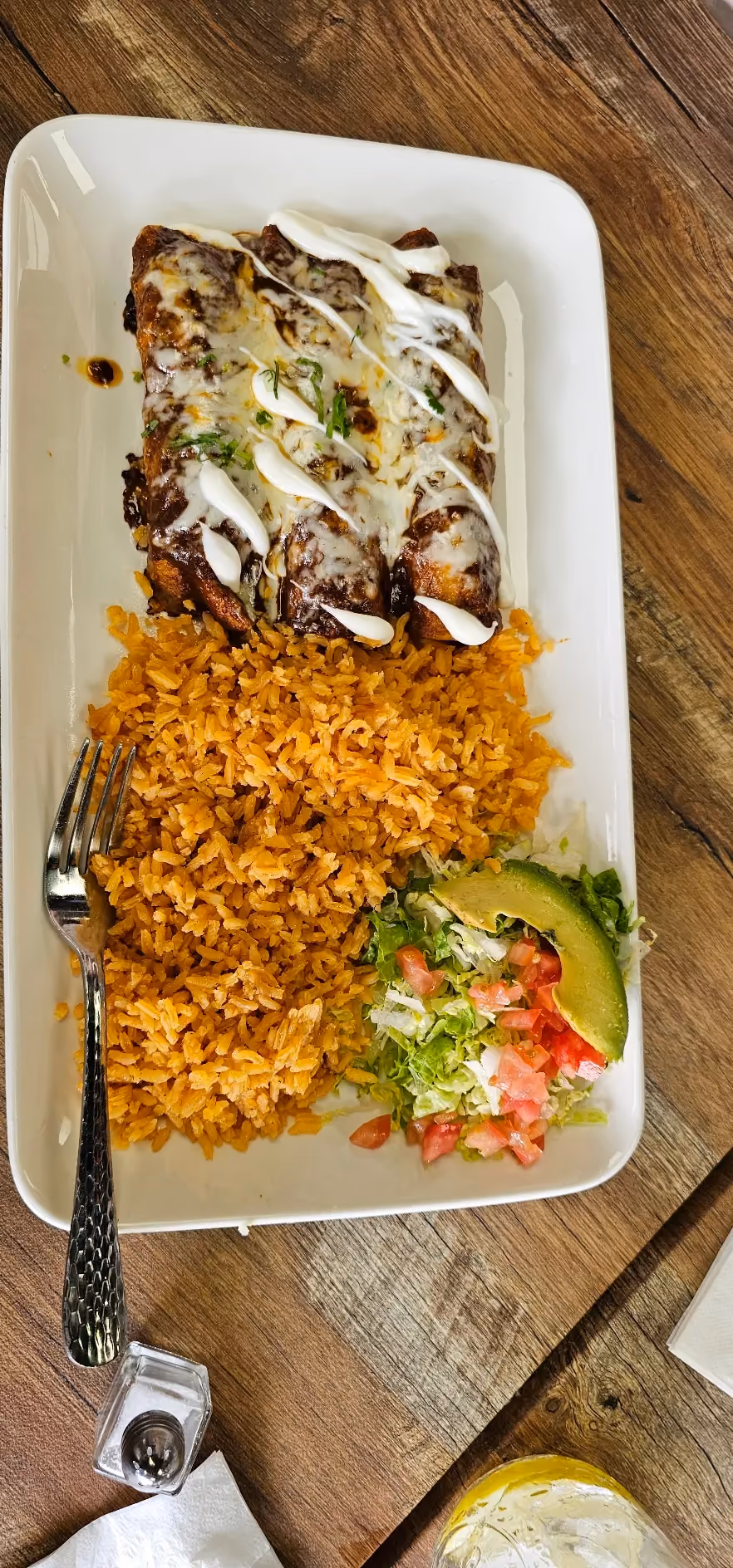 Cheese enchiladas with sour cream drizzle, rice, and a side salad with avocado at Don Chuy's Taqueria