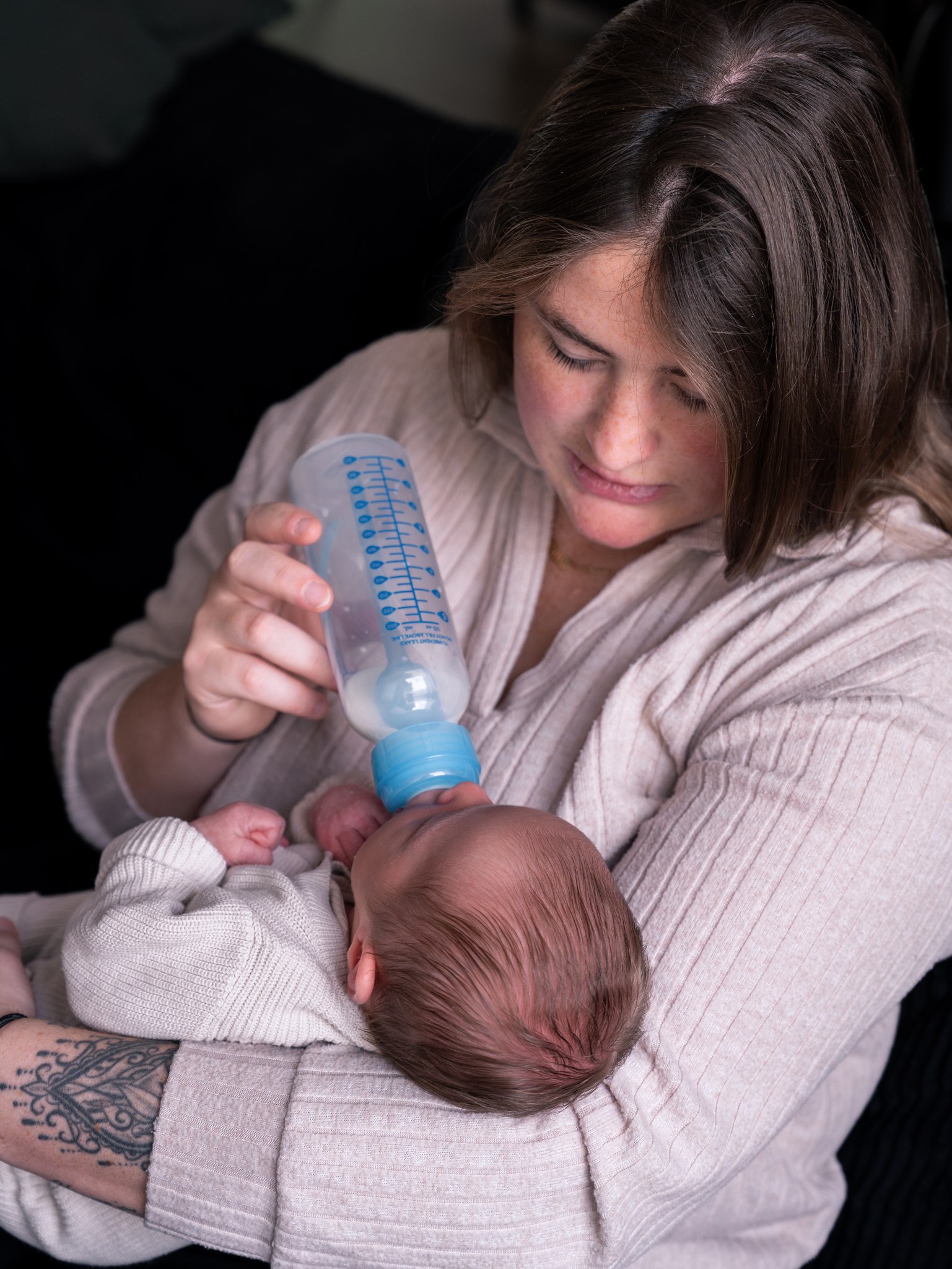 Moeder geeft de baby de fles tijdens de newbornreportage
