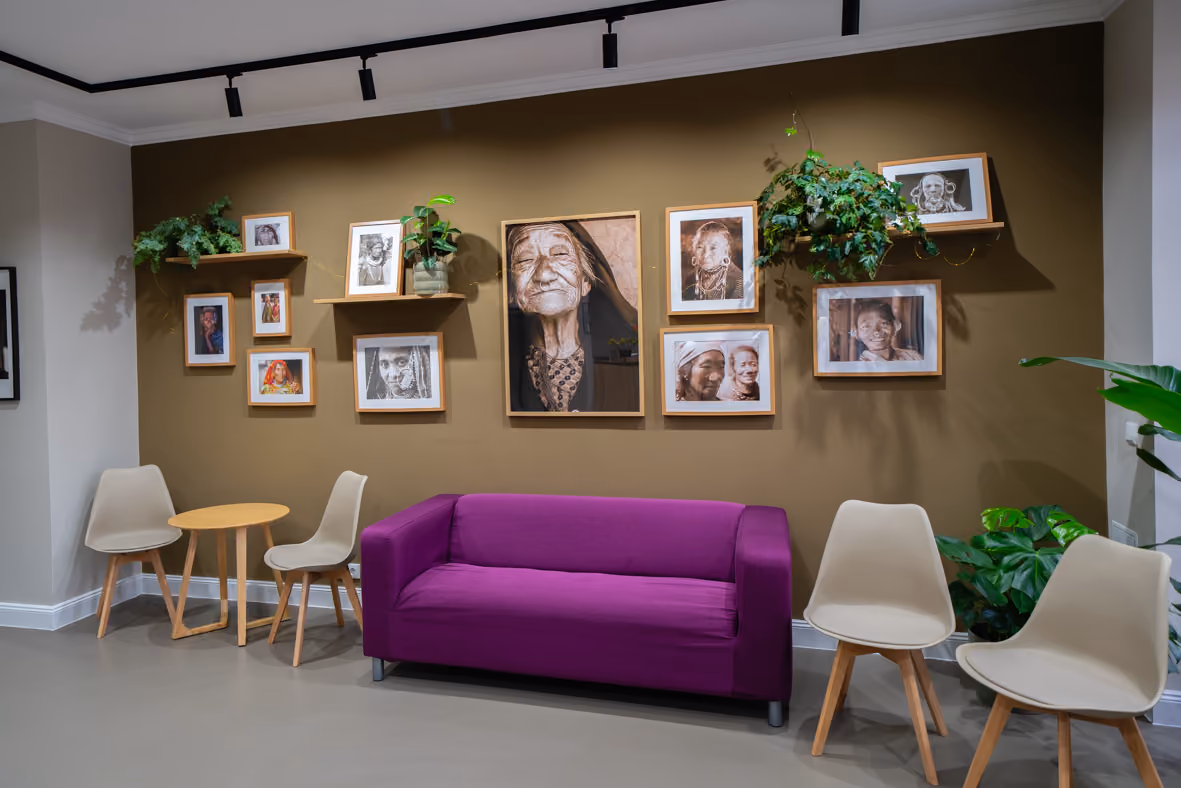 Wartebereich mit lila Sofa, Beistelltisch, Stühlen und Porträtwand, Taboo Piercing Rostock