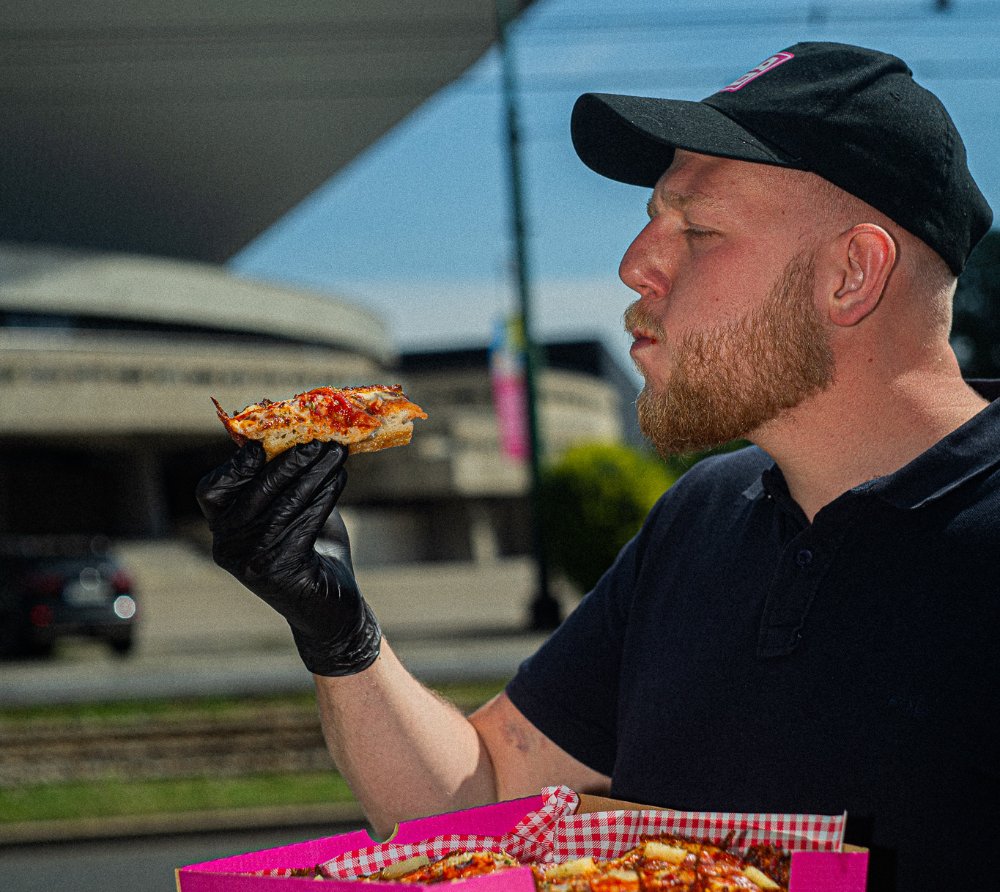 Pracownik Kato Pizza z kawałkiem pizzy przed Spodkiem w Katowicach