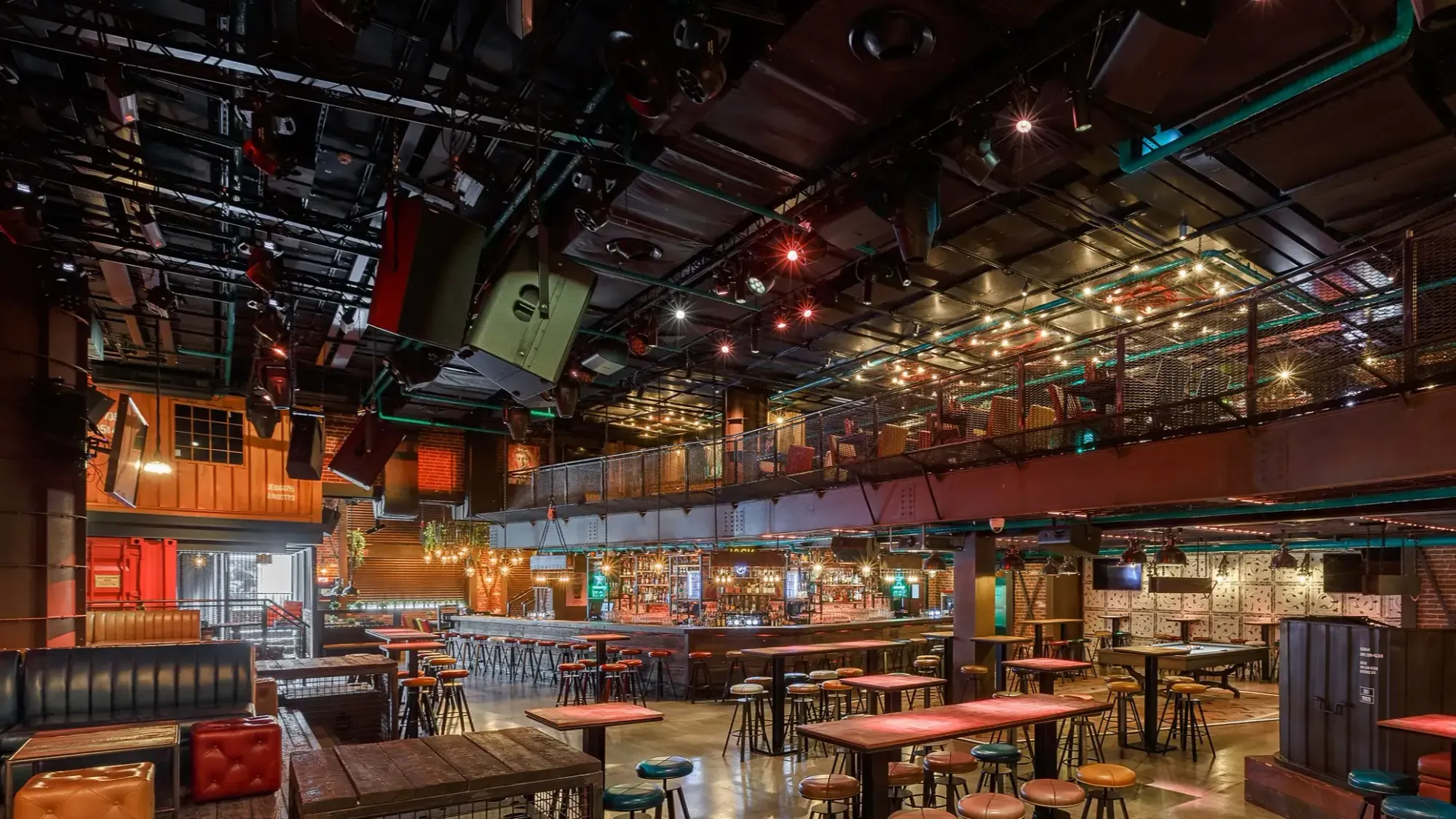 Multi-level bar and lounge venue with exposed ceiling services and suspended speakers