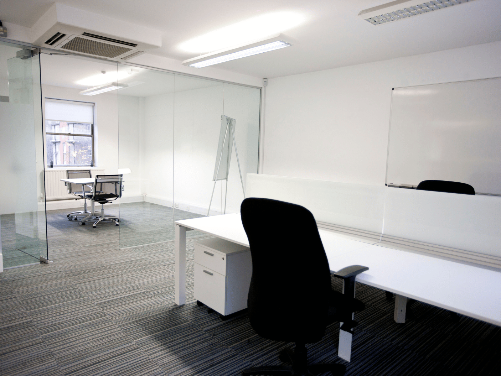 Leeres Büro mit Glaswänden, Schreibtischen und Whiteboard