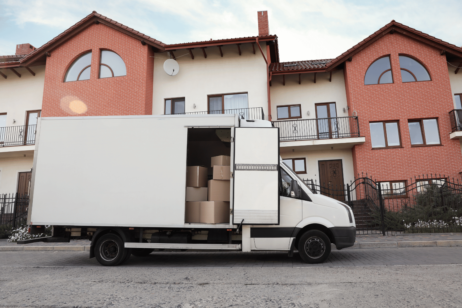 Umzugs-Lkw mit geöffneter Seitentür und gestapelten Kartons am Straßenrand