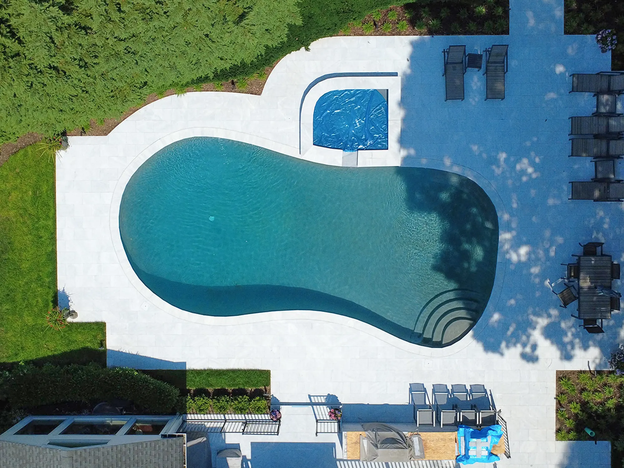 Aerial view of Ice White marble pavers surrounding a curved swimming pool and outdoor seating areas.