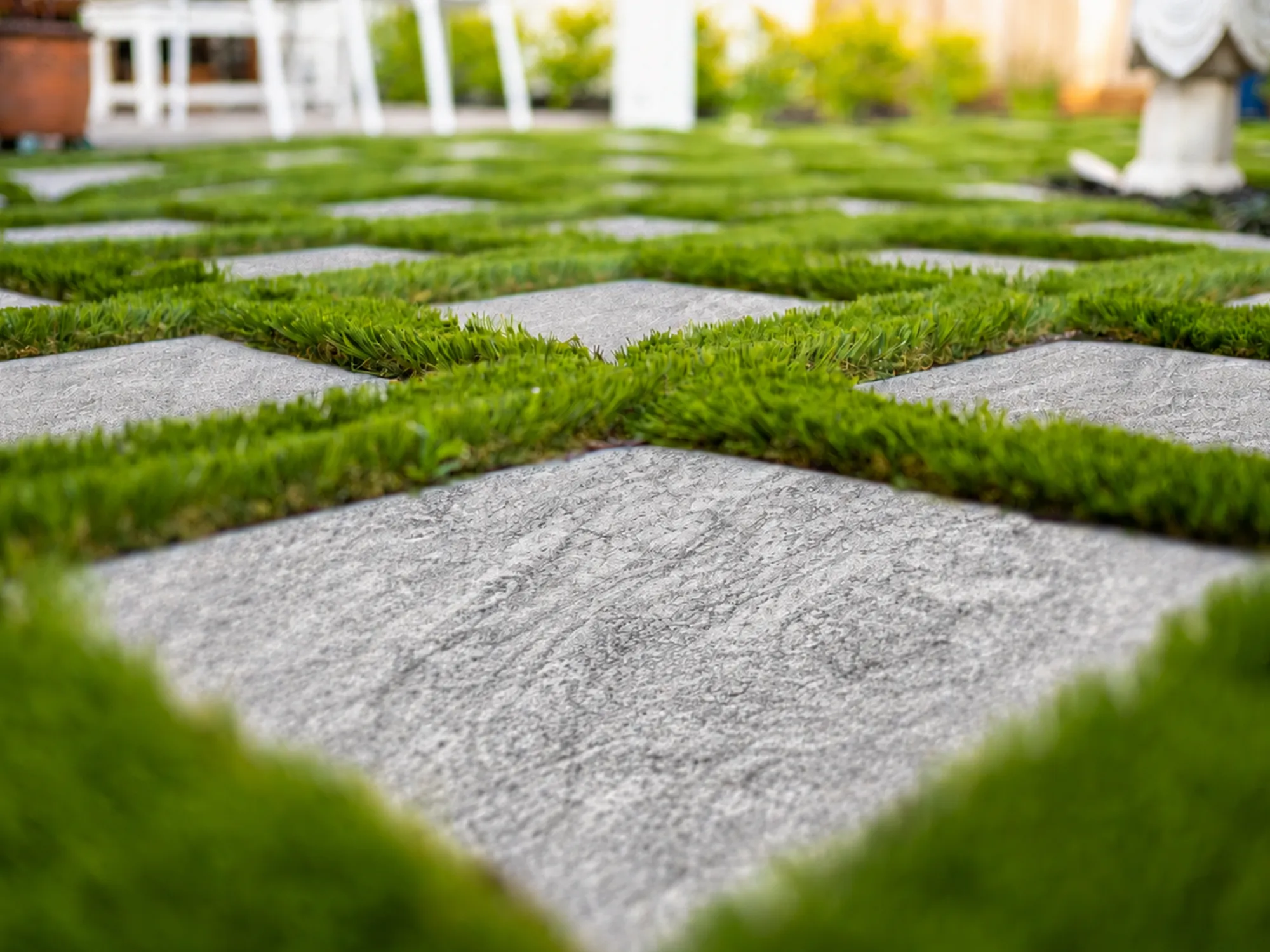 Square Silver Mist marble pavers with flowing gray and white markings, set between strips of green grass.