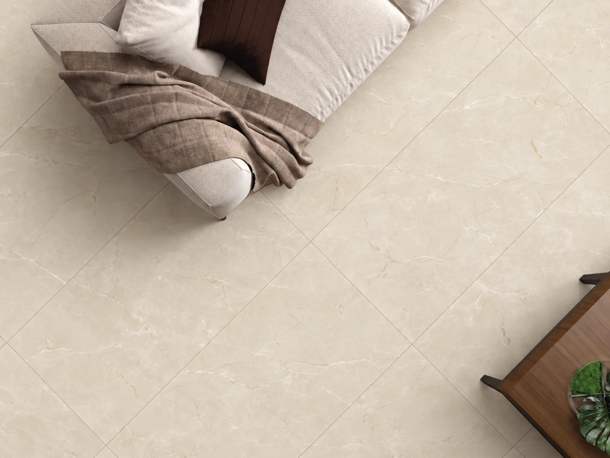Overhead view of Sundein Beige marble floor tiles beside a cream sofa with a taupe throw and a wooden console.